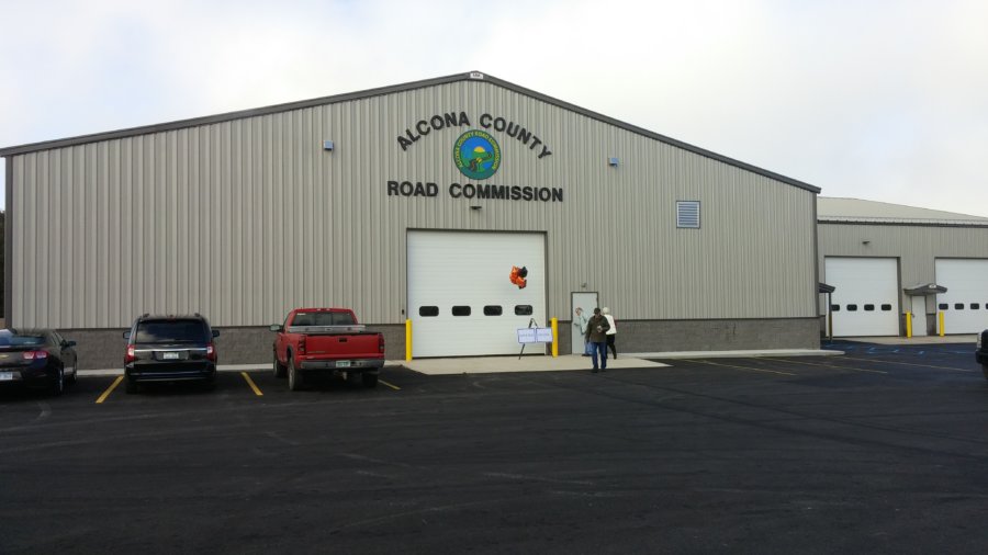A truck parked in front of a building with the words alcona county road commission on it.