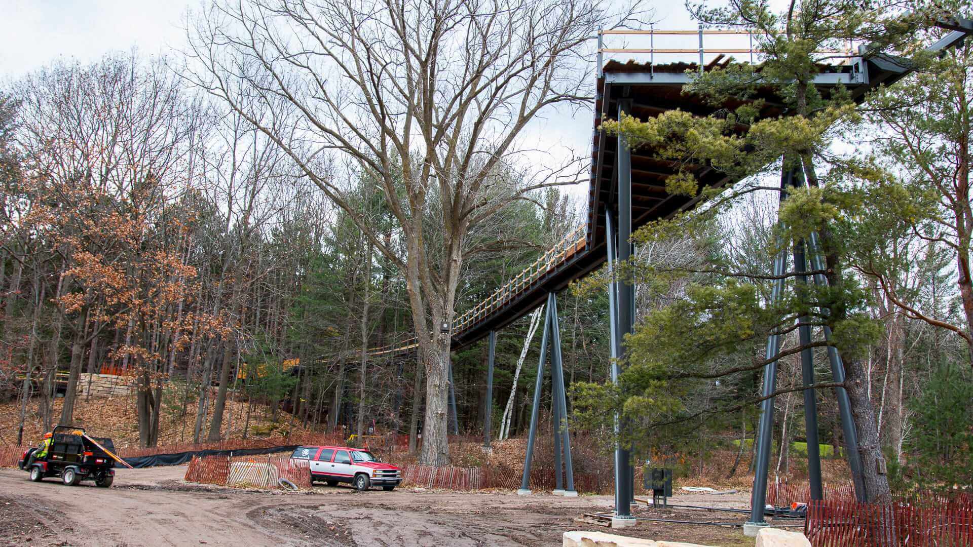 A bridge with cars parked below and trees all around